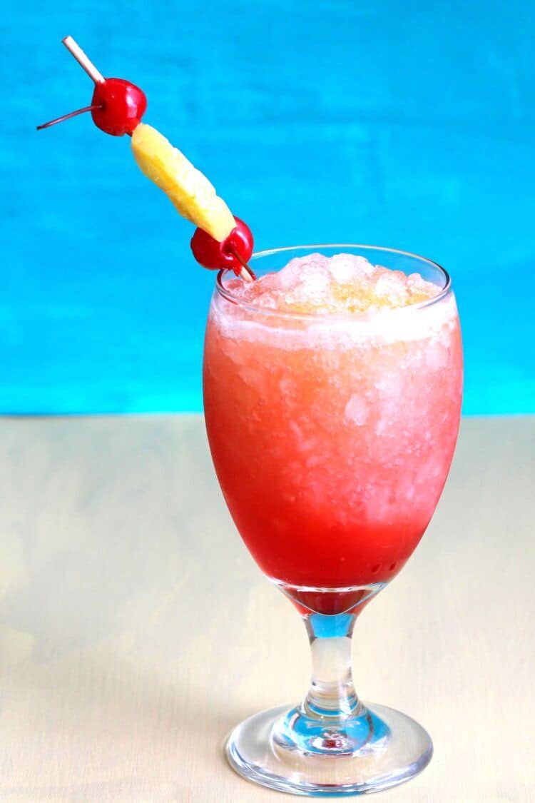 Kiss on the Lips drink in goblet with pineapple and cherry garnish